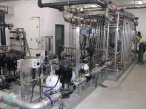Interior of water treatment plant. There are a series of pipes throughout the room.